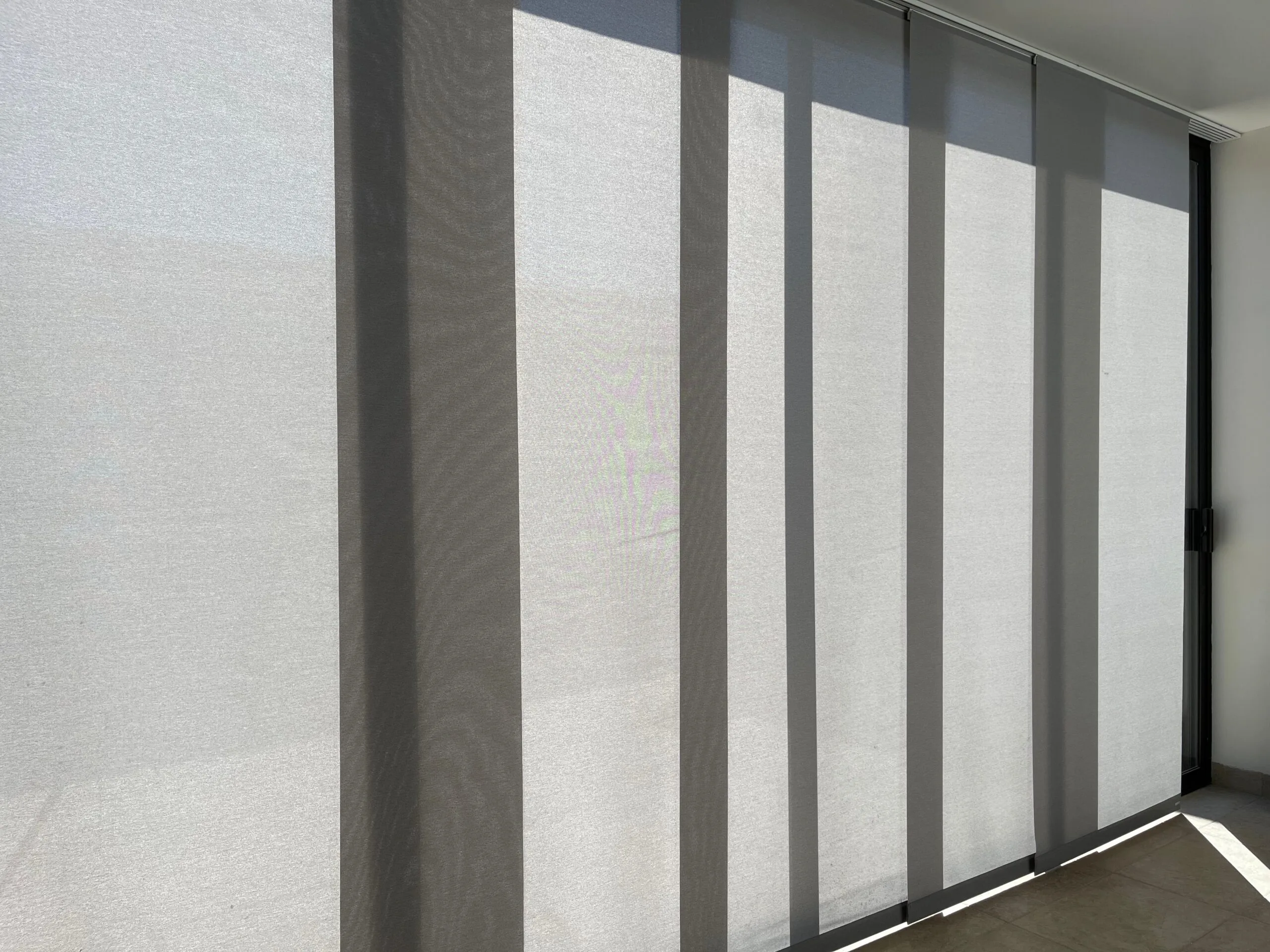 Light grey panel glide blinds covering a large window installed by Australian Plantation Shutters