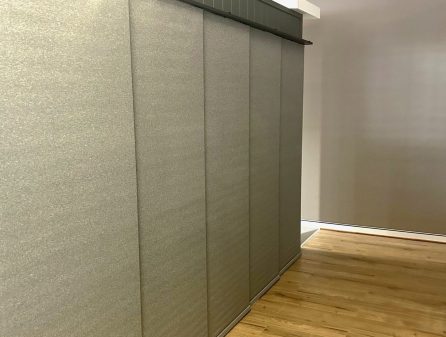 Light grey panel glide blinds covering a large window installed by Australian Plantation Shutters